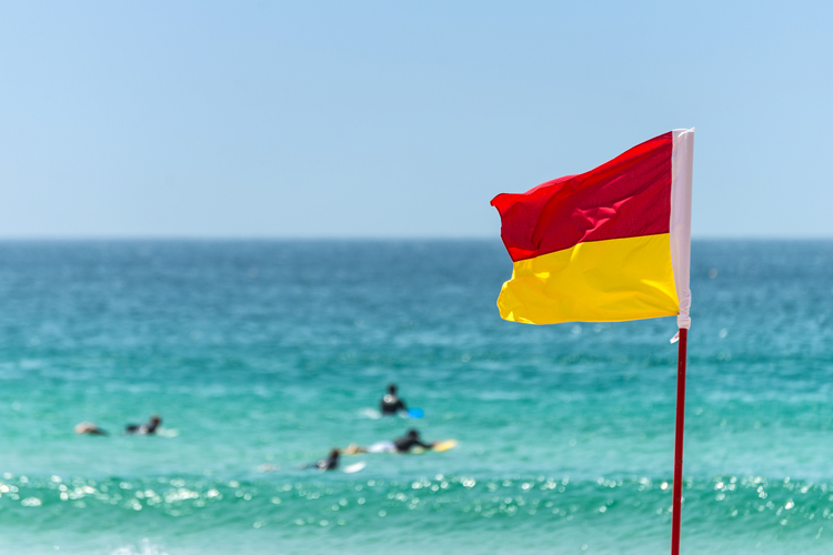 2 orange and red flags on a beach